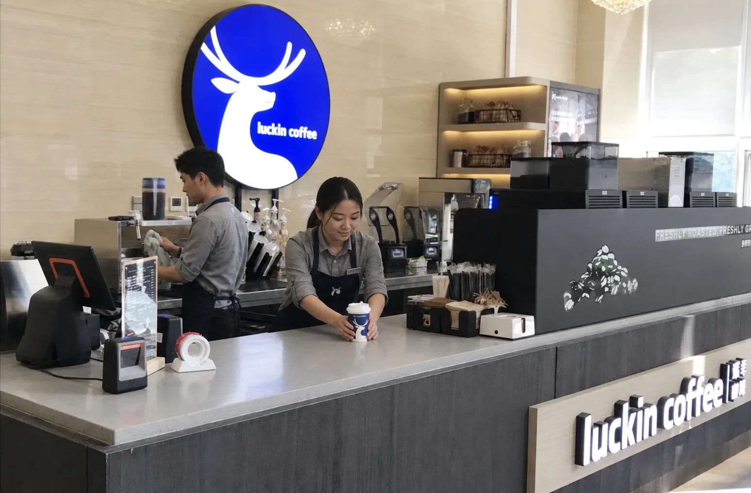 Deux employés préparant et déposant une commande dans un établissement Luckin Coffee