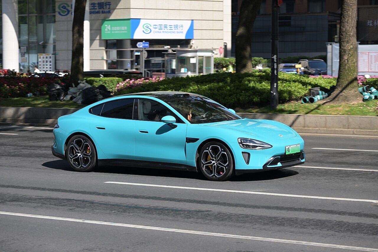 Blue Xiaomi SU7 sedan driving on a Shanghai street