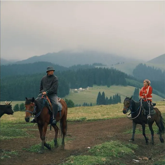 Riders crossing a summer mountain pasture